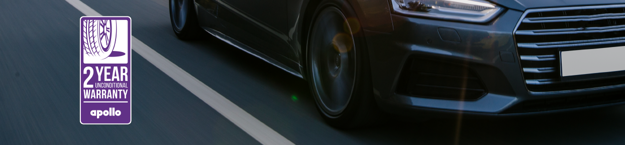 apollo warranty promotion banner: a black car driving down the road with focus on the tyres.