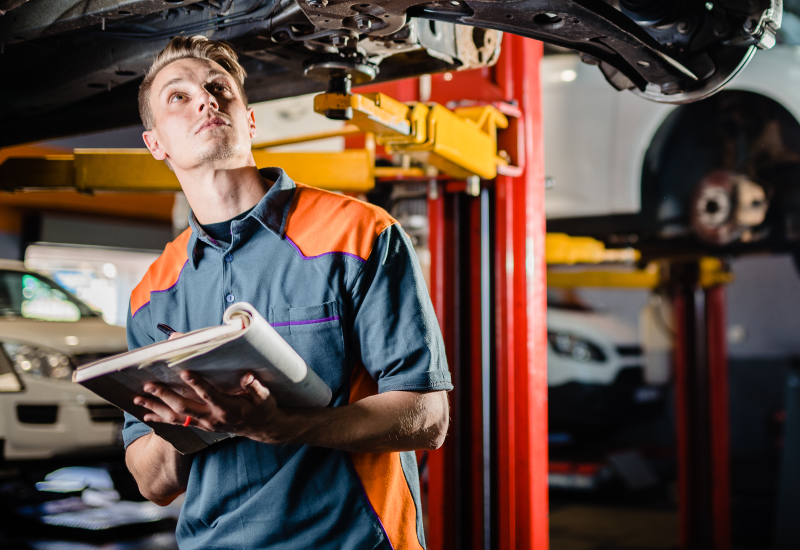 A tyres & more technician looking beneath a lifted vehicle